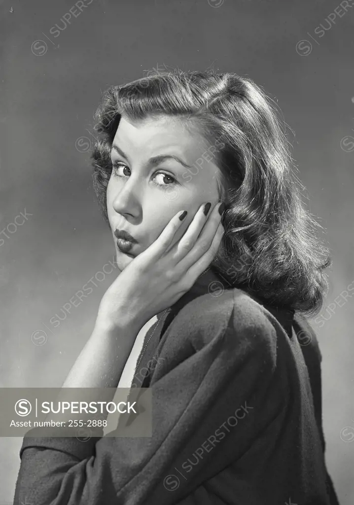 Vintage Photograph. Woman with left arm raised and hand on cheek with pursed lips in surprised expression
