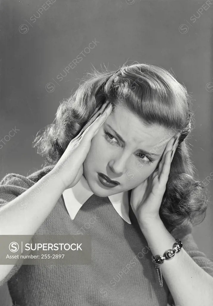 Vintage Photograph. Woman wearing sweater over white collared shirt holding up hands to face looking distressed