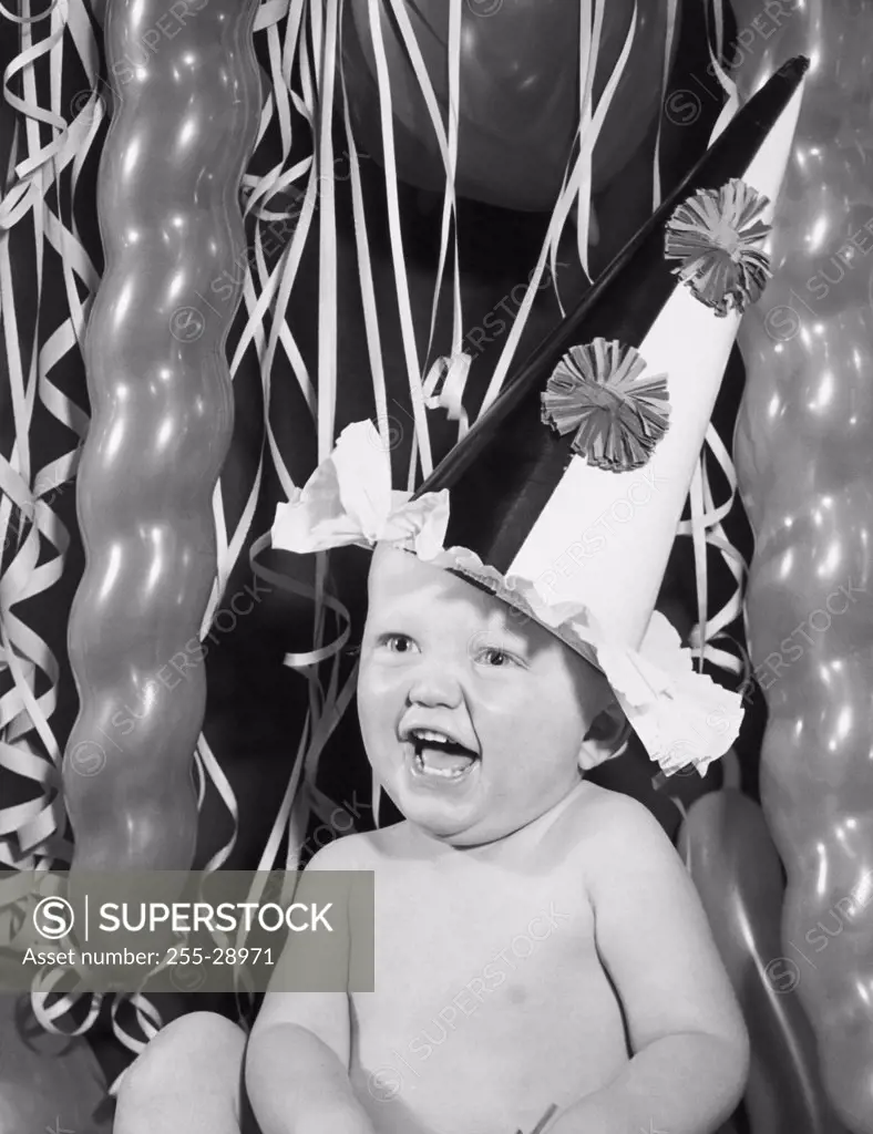 Close-up of a baby boy wearing a party hat and laughing