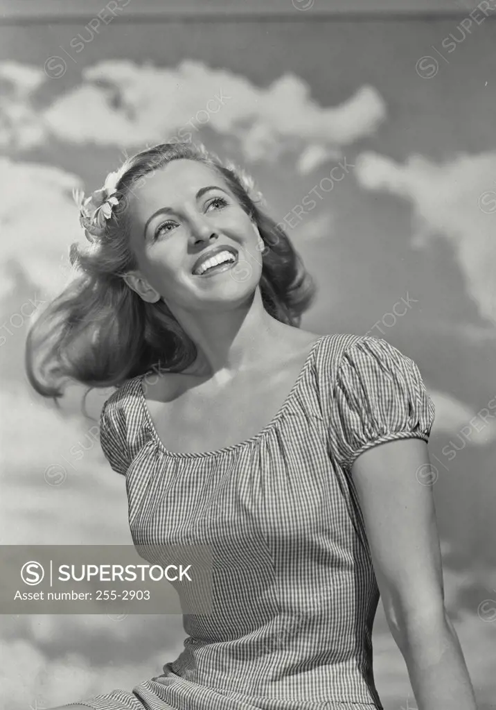 Vintage photograph. Close-up of a young woman in blouse smiling off camera with clouds in background