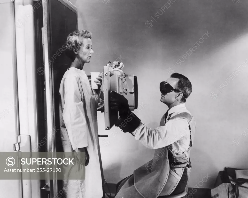 Side profile of a male radiologist taking an x-ray of a female patient