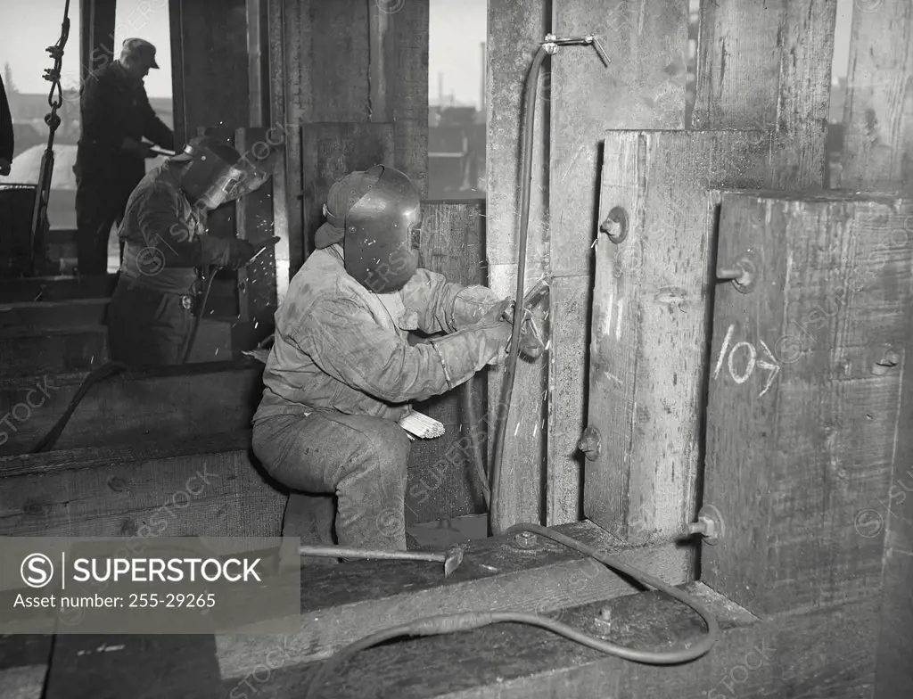 Vintage photograph. Side profile of people welding copper dam