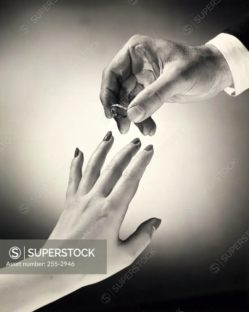 Close-up of a man's hand placing a ring on a woman's finger