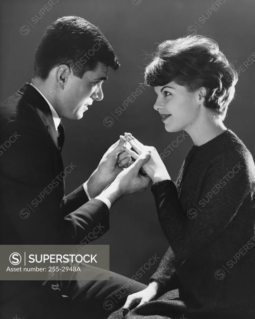 Side profile of a young man putting a ring on a young woman's finger