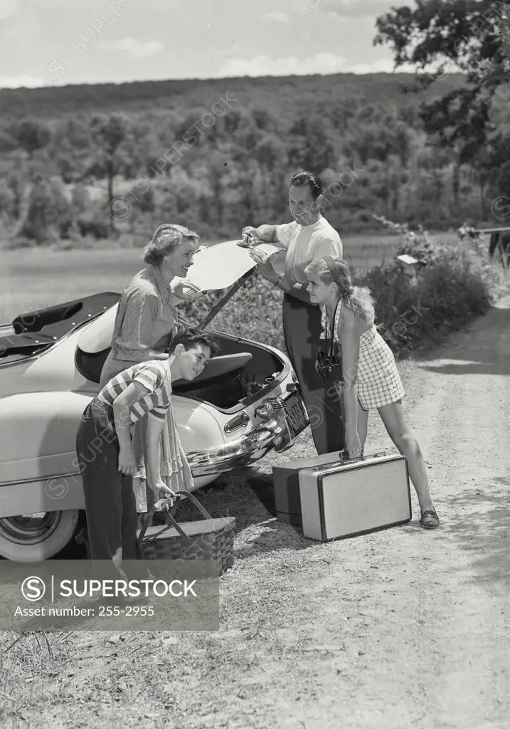 Vintage photograph. Family unloading picnic supplies from trunk