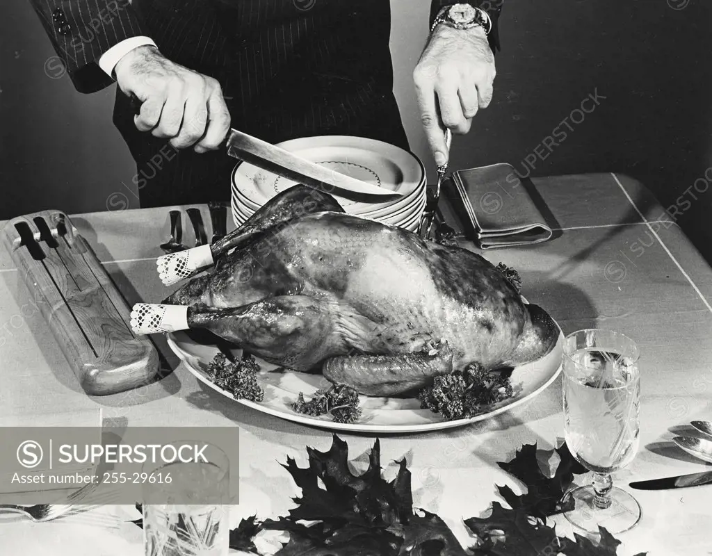 Vintage photograph. Close-up of a man cutting a roasted turkey on Thanksgiving day