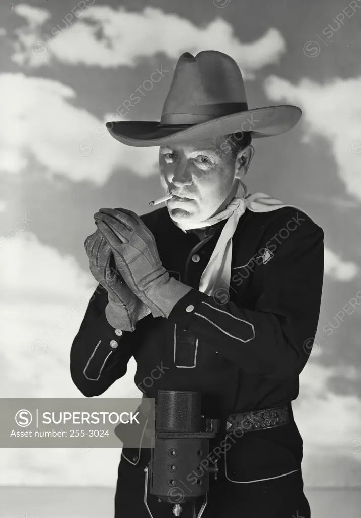 Vintage Photograph. Man in cowboy outfit with hat and gloves smoking cigarette