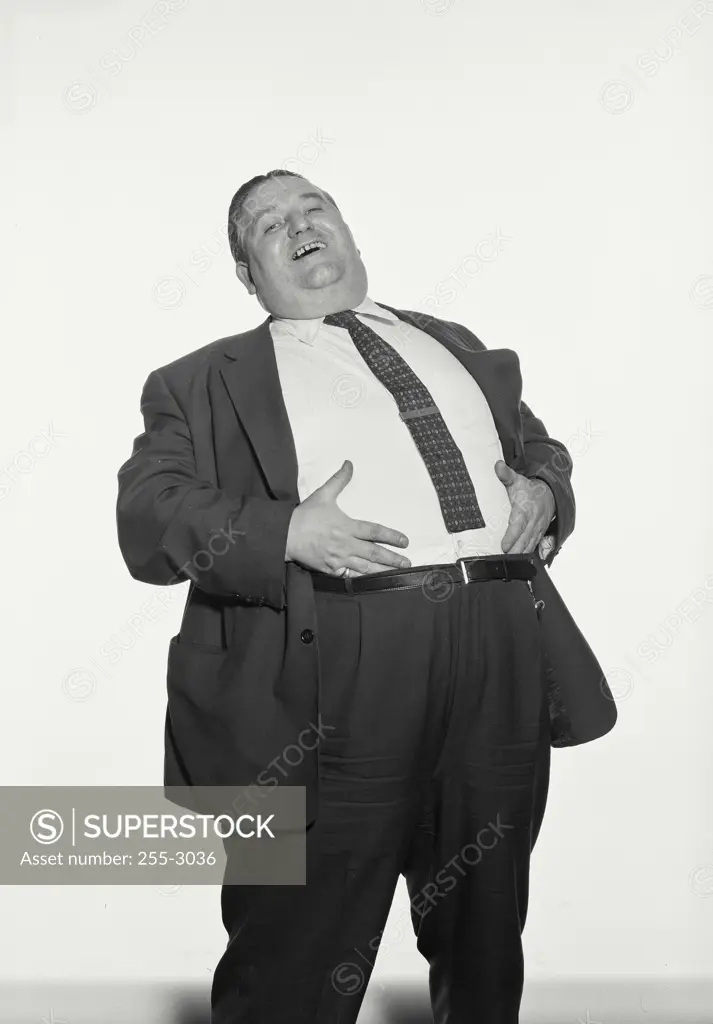 Vintage Photograph. Fat man wearing suit and tie laughing with hands on stomach