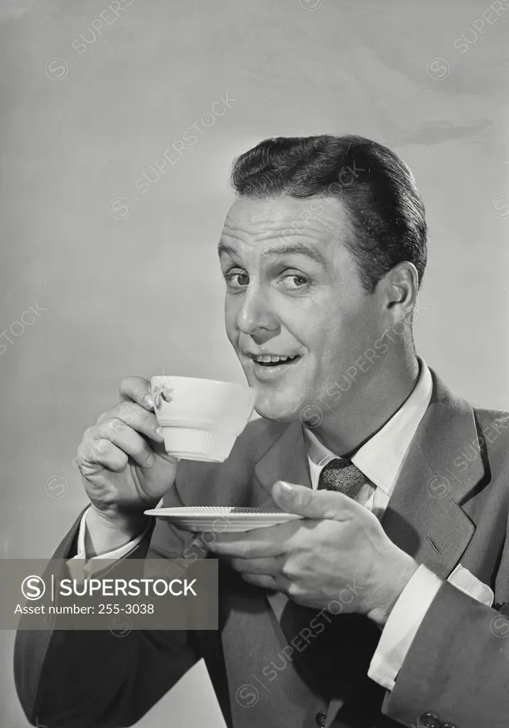 Vintage Photograph. Man in suit and tie holding teacup and saucer