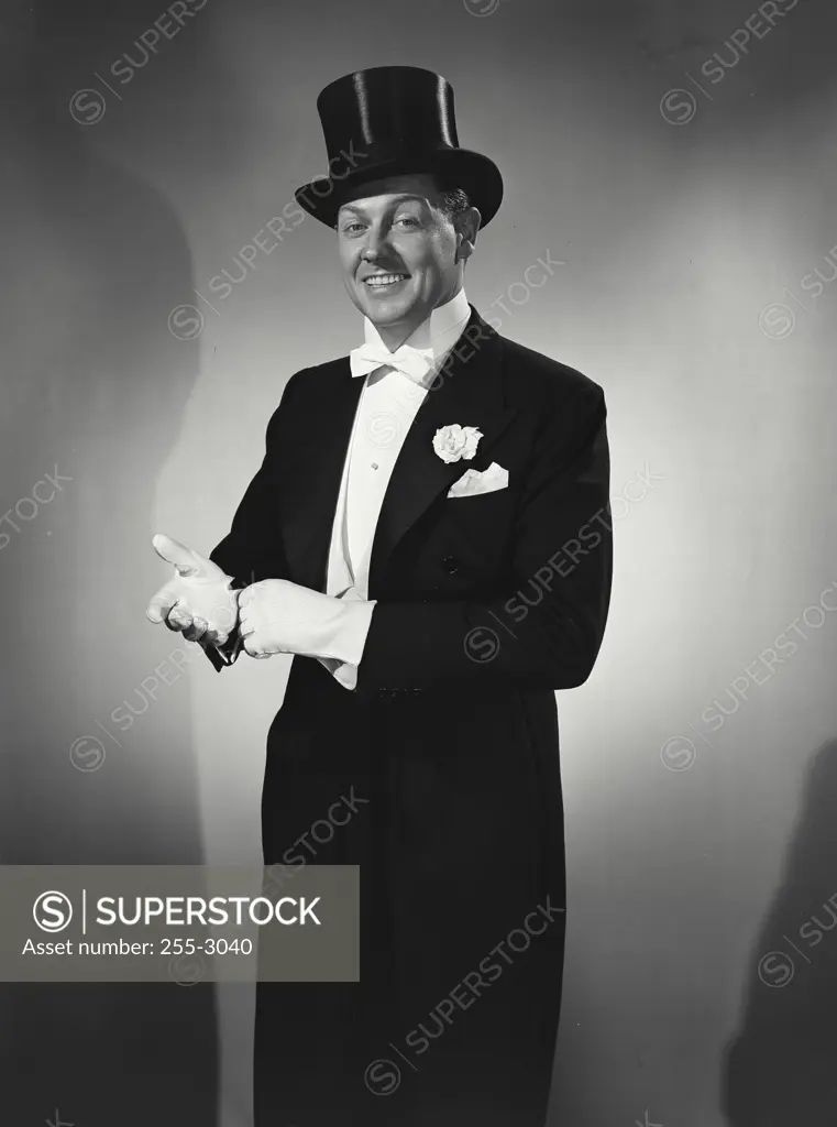 Vintage photograph. Man in tuxedo and top hat adjusting cuffs