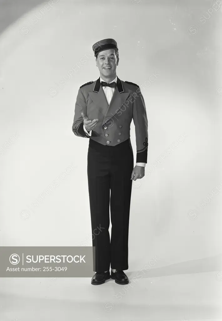 Vintage Photograph. Man wearing bellman uniform standing on white background