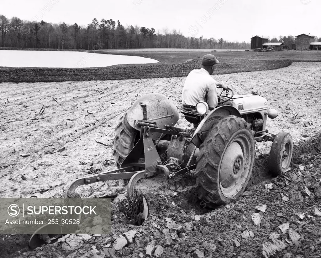 Rear view of a farmer plowing a field with a tractor