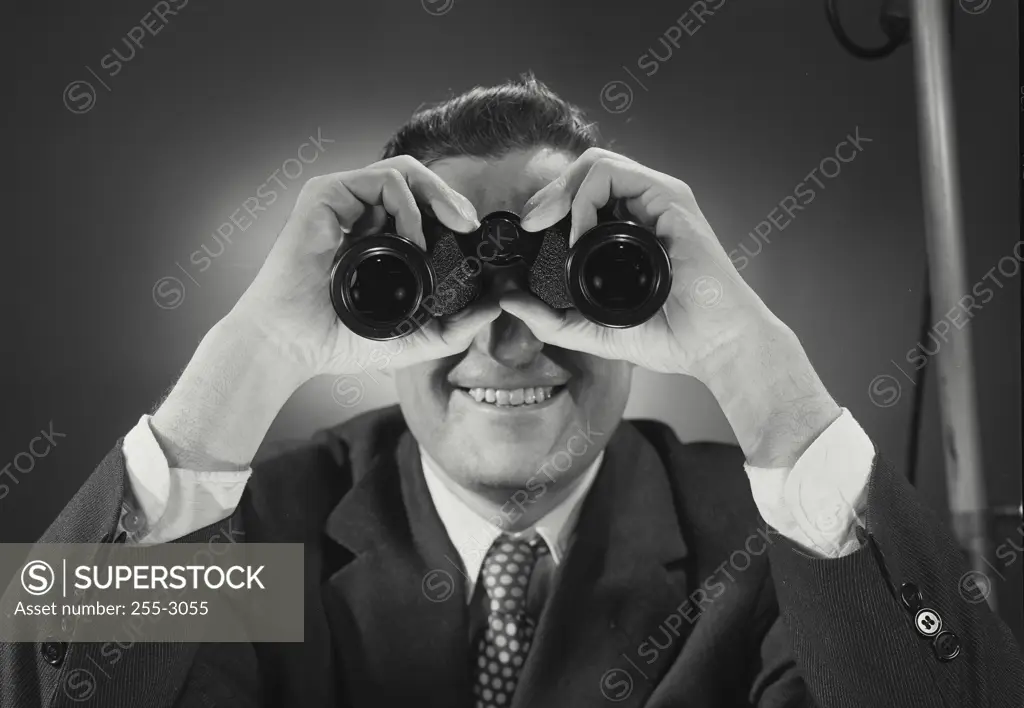 Vintage Photograph. Man in suit and tie looking through binoculars. Frame 1