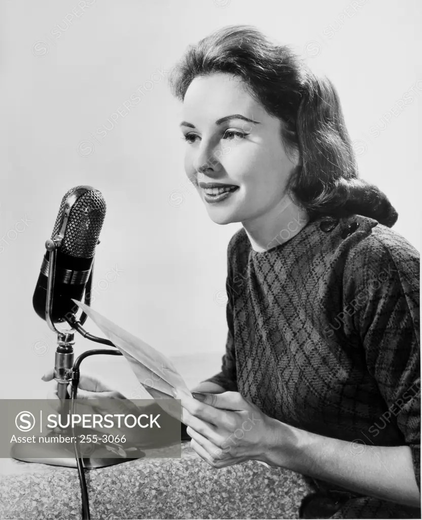 Mid adult woman speaking into a microphone