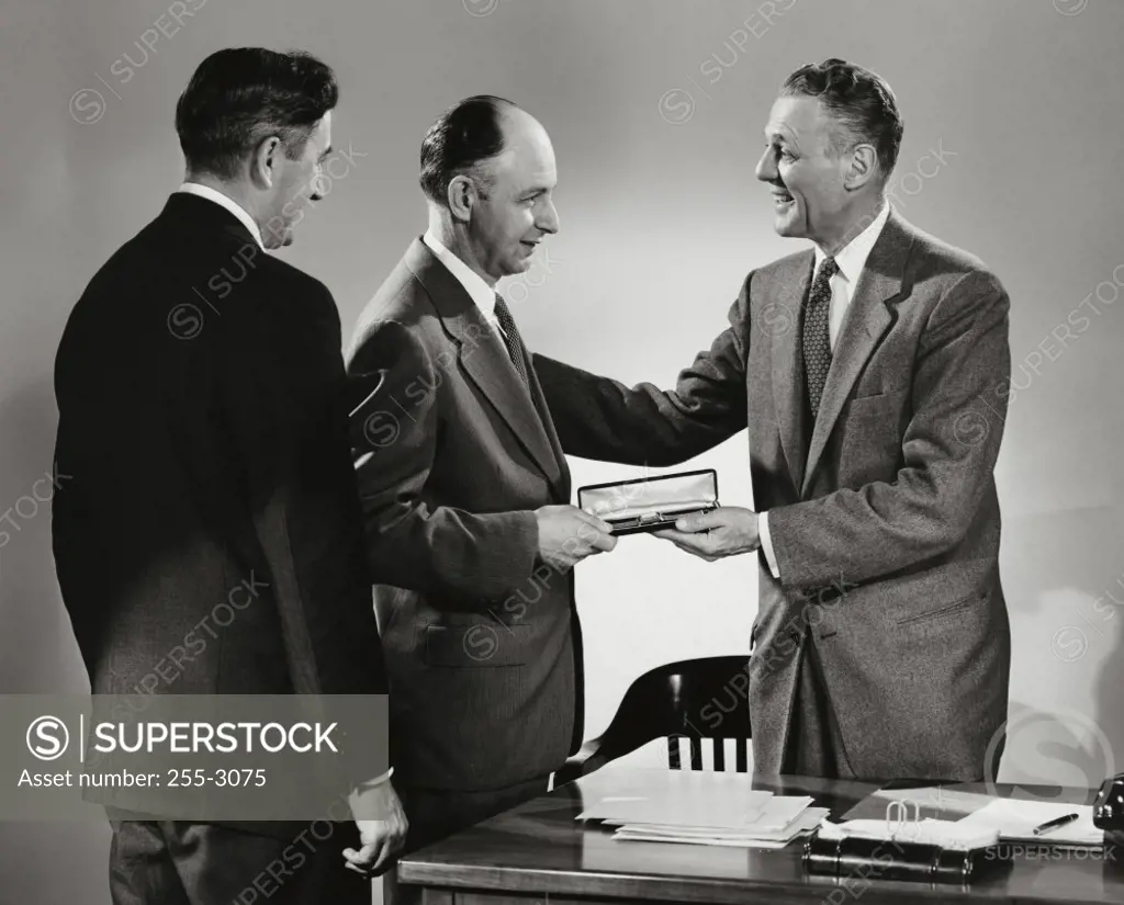 Side profile of a businessman presenting a gift to another businessman