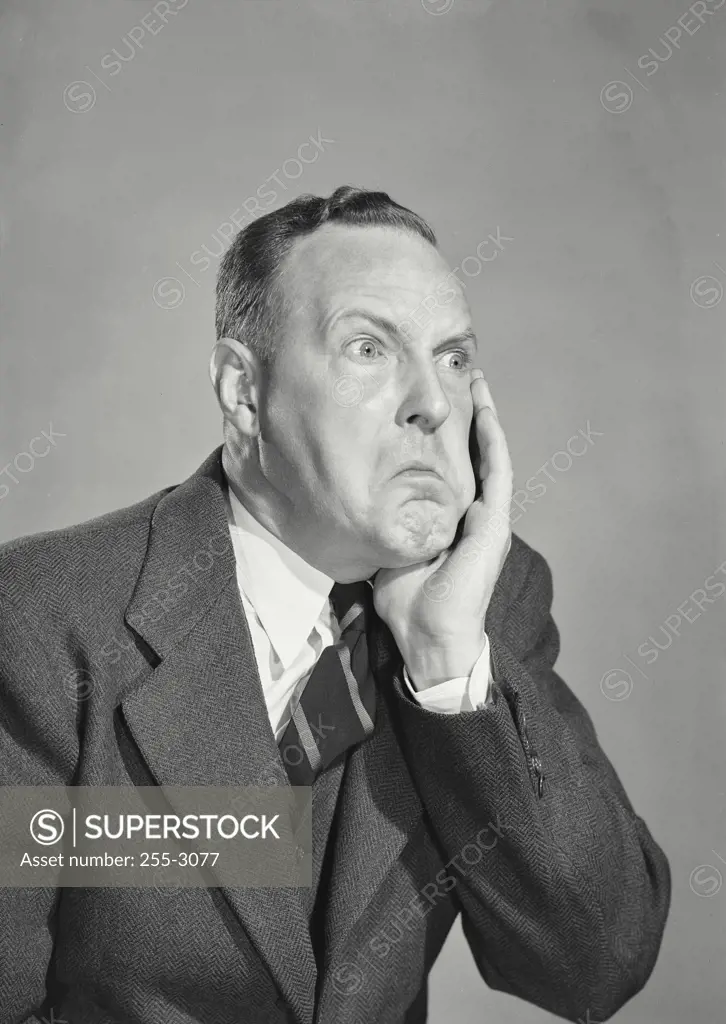 Vintage Photograph. Man in suit holding up hand to cheek in pain with humorous wide eyed expression