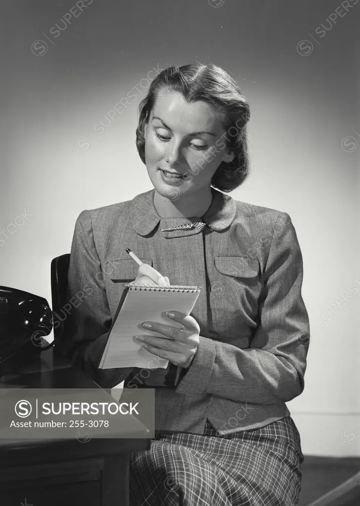 Vintage photograph. Woman with short hair writing on note pad.