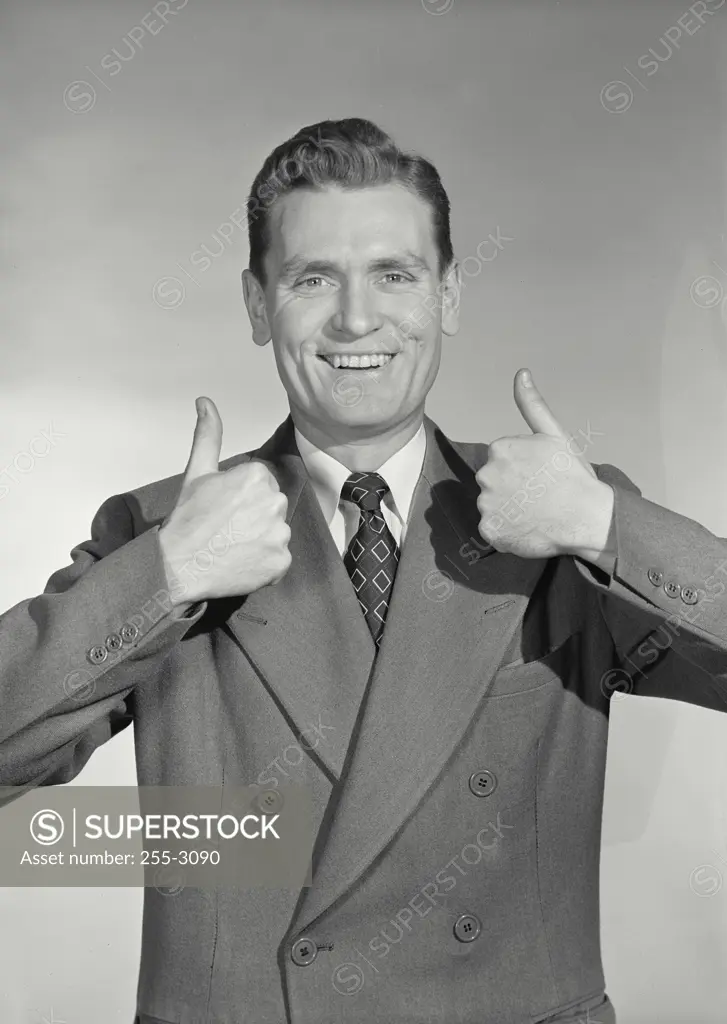 Vintage Photograph. Man in suit and tie holding up both hands making thumbds up gesture