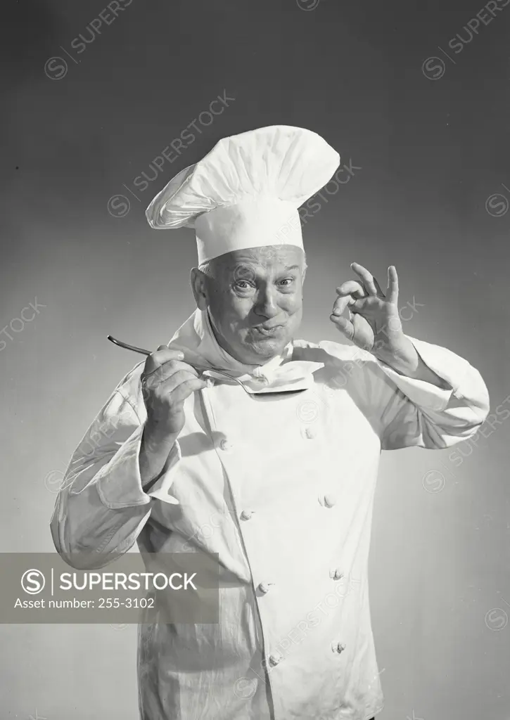 Vintage photograph. Man in chef uniform tasting spoon