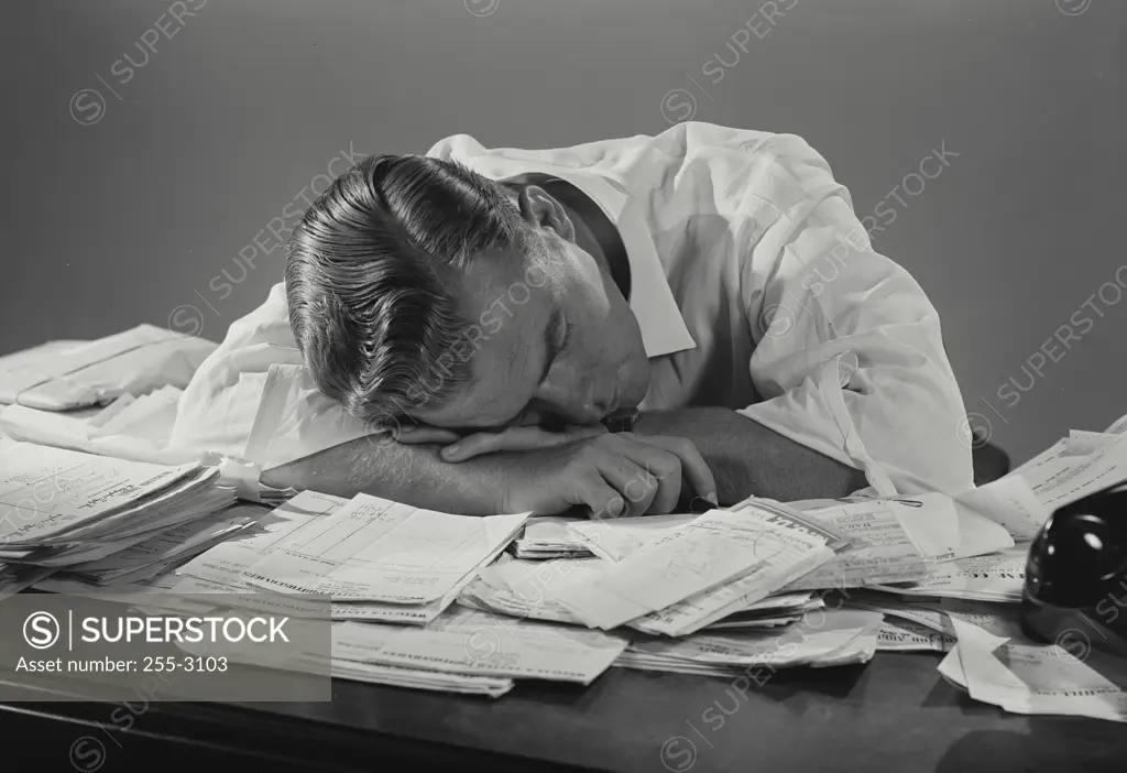 Vintage Photograph. Businessman working at office desk laying down on documents