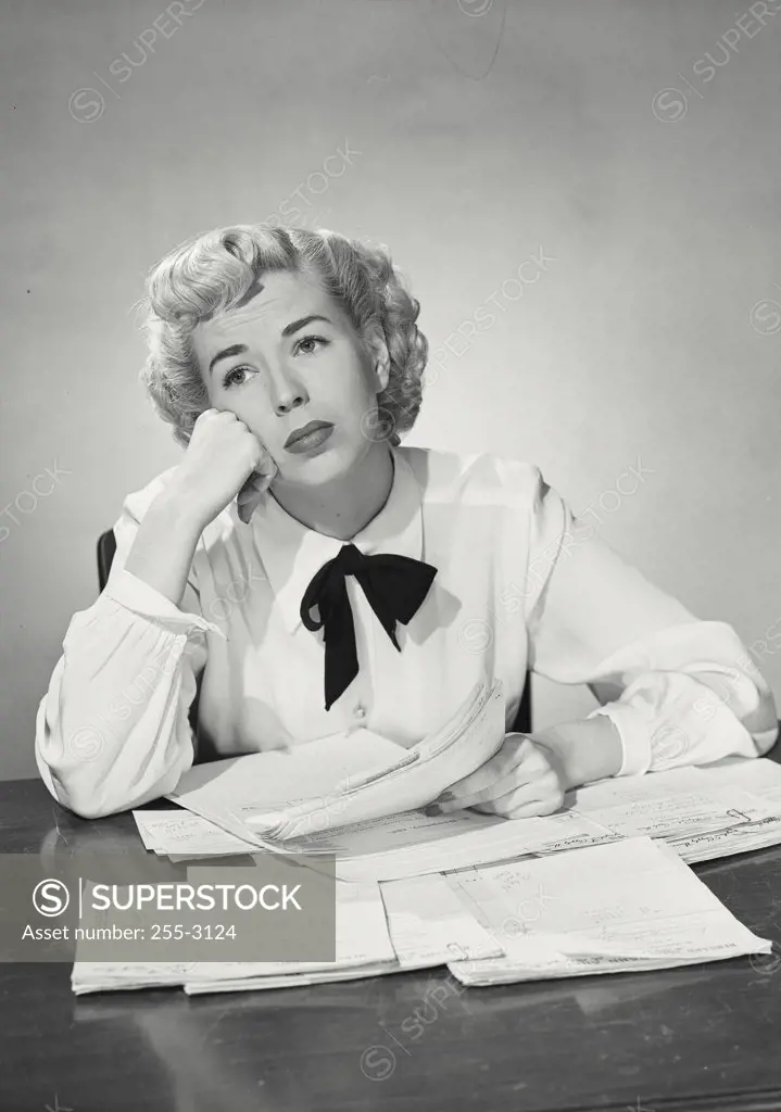Vintage photograph. Woman in button shirt and western bowtie sitting at desk