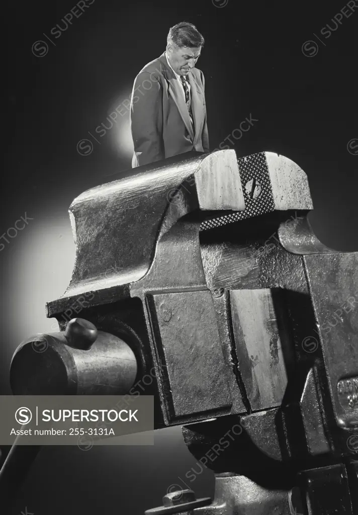 Vintage Photograph. Photo-illustration showing man in suit wedged in between vice clamp