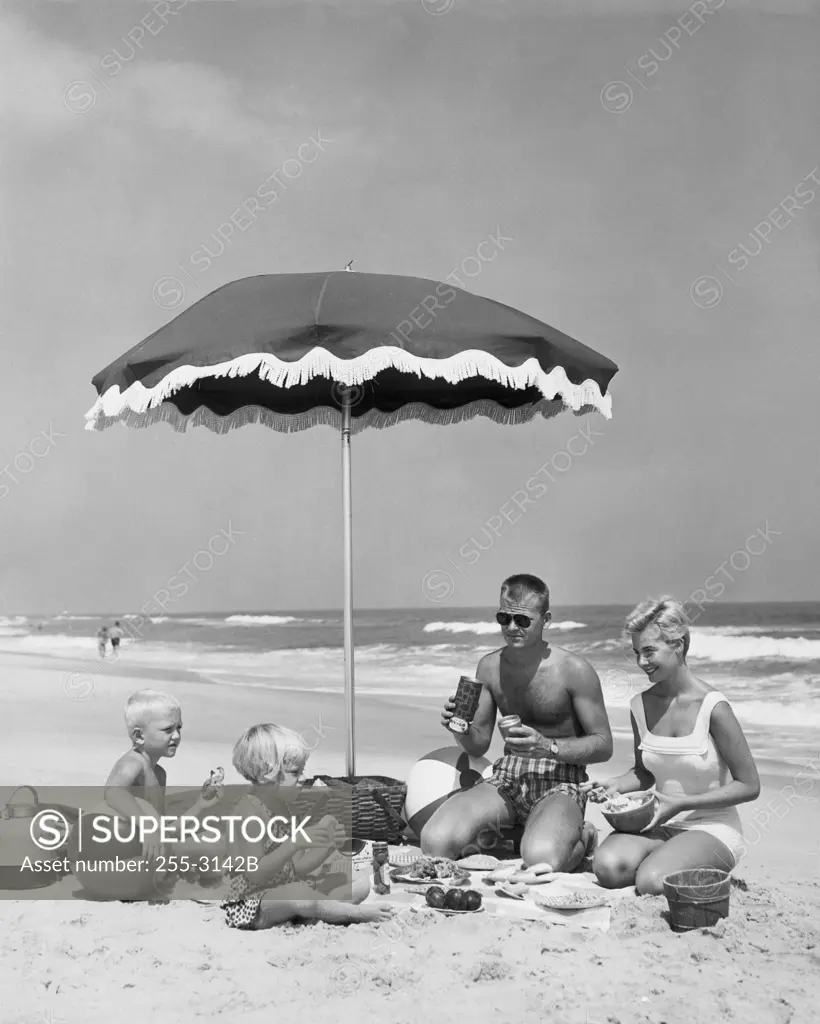 Mid adult couple with two children at picnic on beach