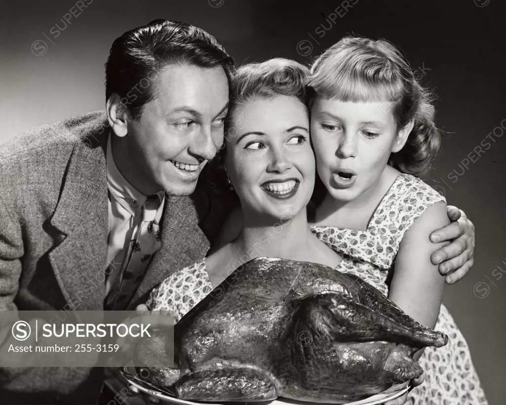 Portrait of a family holding a turkey on a platter