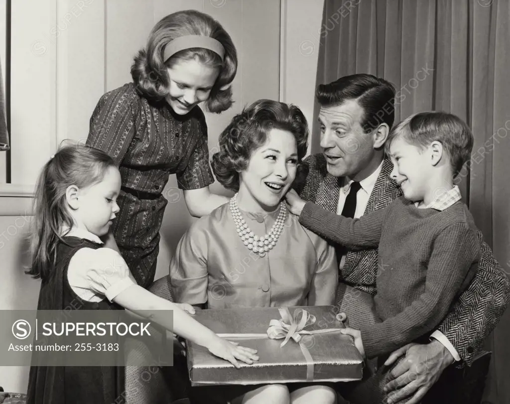 Close-up of a mature woman holding a birthday present with her family beside her