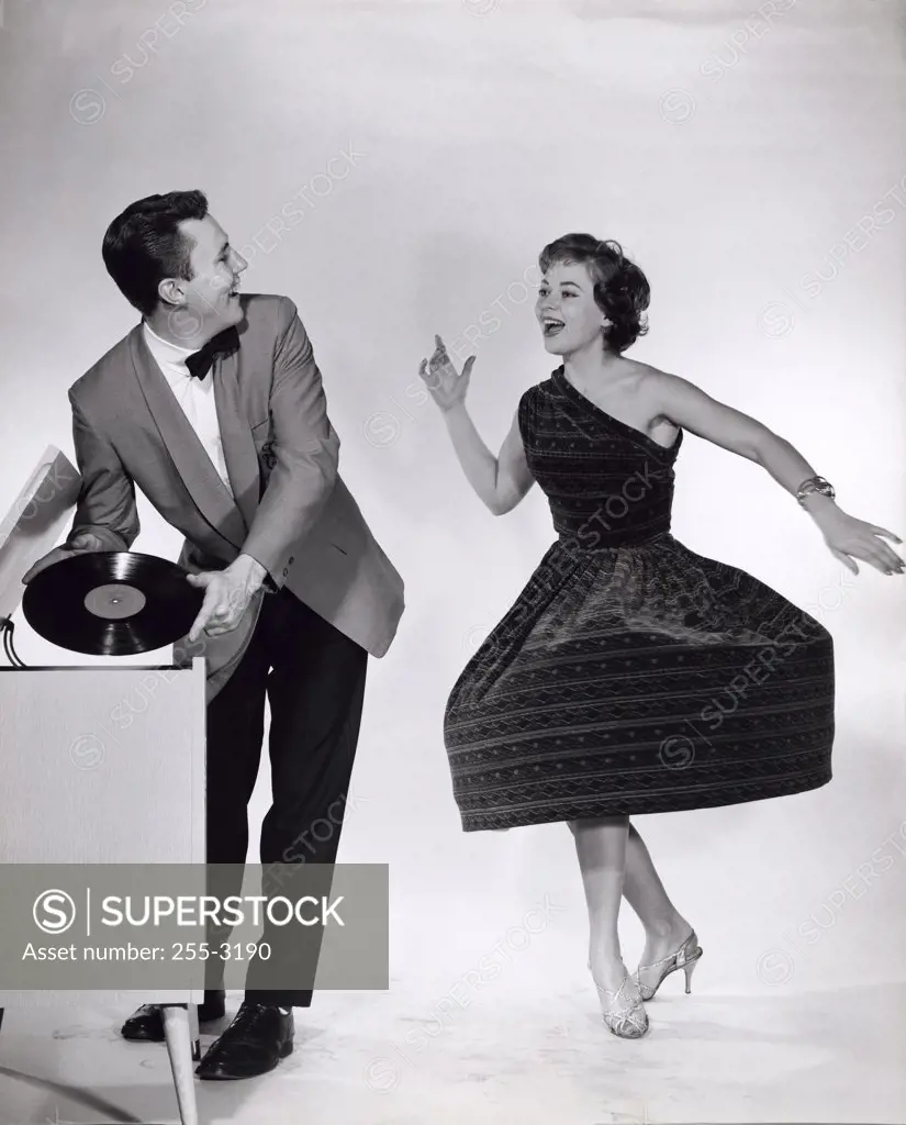 Young man holding a record looking at a young woman dancing near him