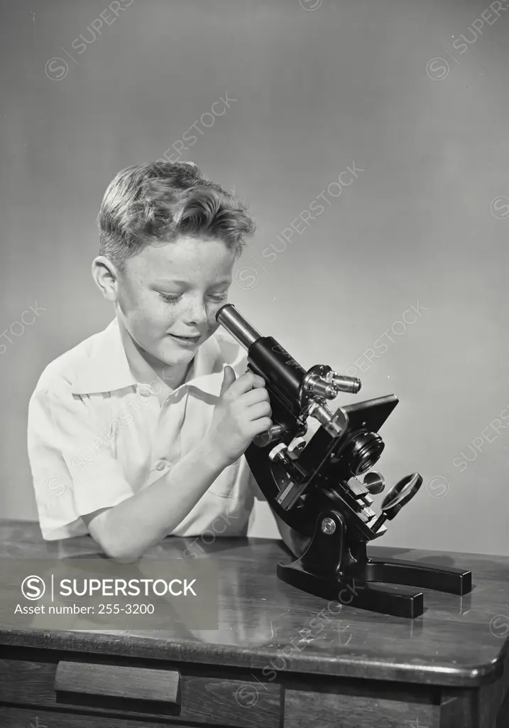 Vintage Photograph. young boy looking into microscope on table