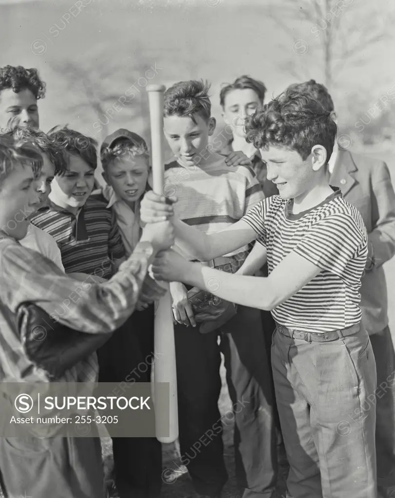 Vintage photograph. Side profile of two boys holding a baseball bat