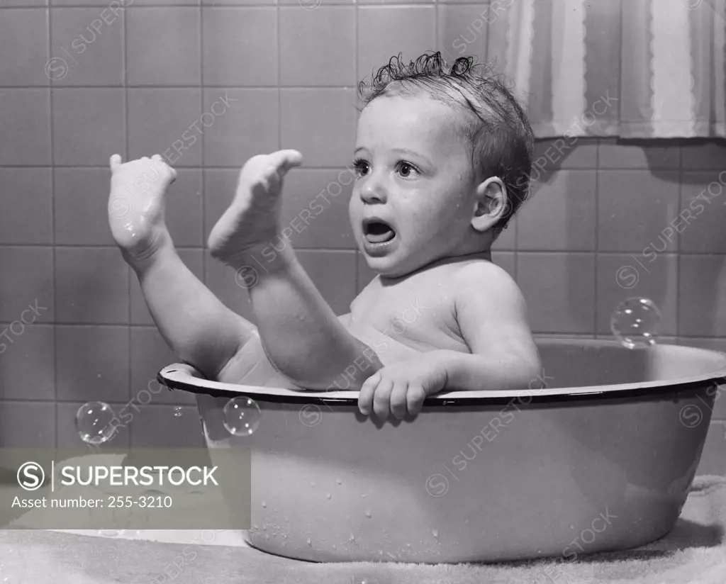 Close-up of a baby boy in a bathtub with his feet up