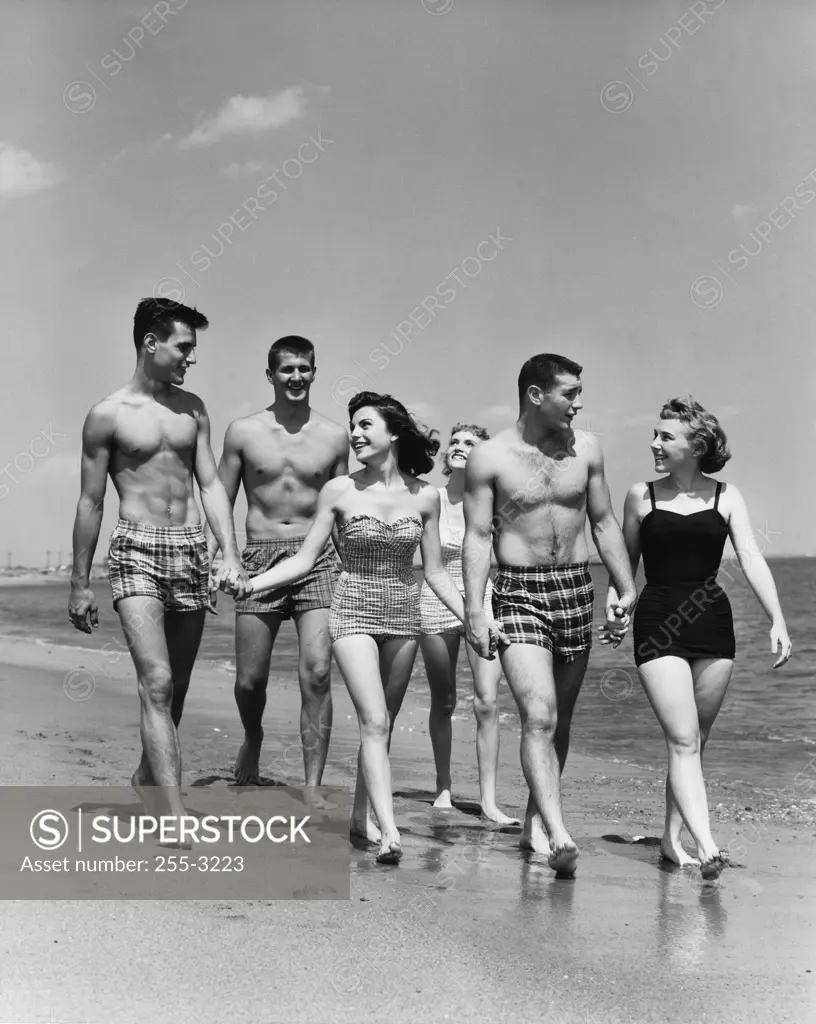 Three teenage couples walking on beach