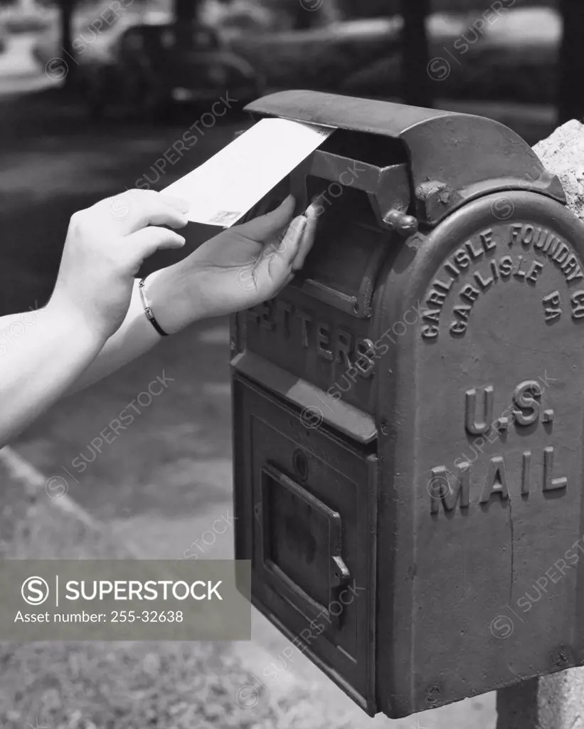 Close-up of a person's hand dropping a letter into a mailbox