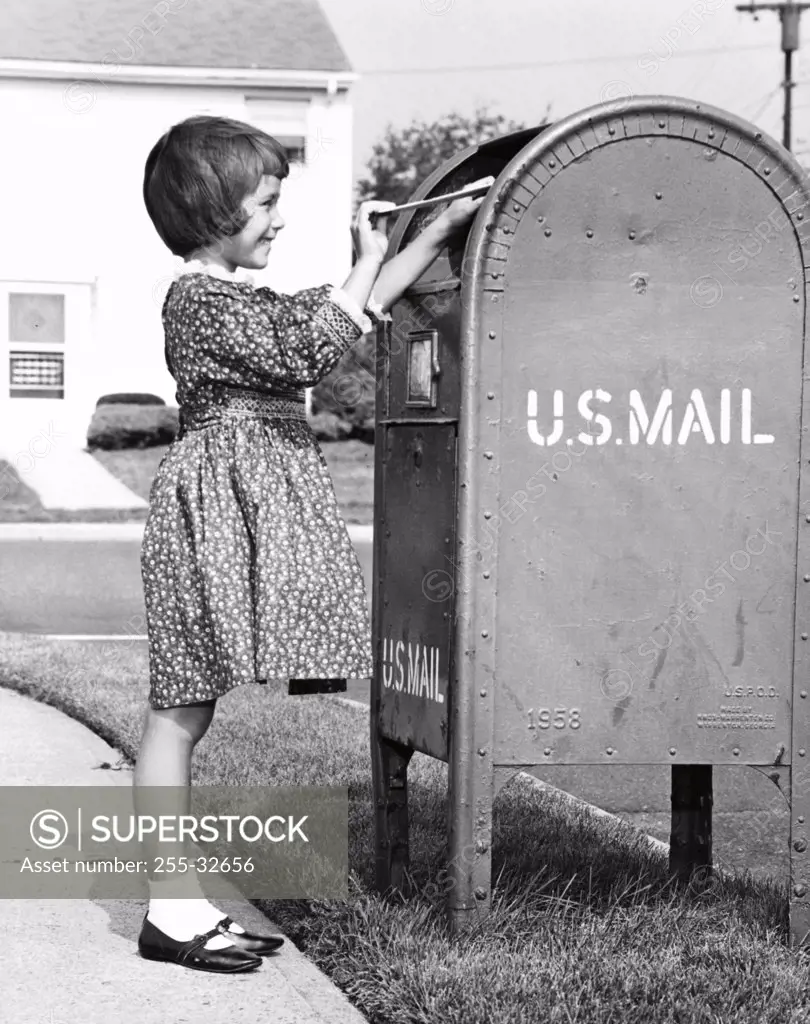 Girl putting a letter into a mailbox