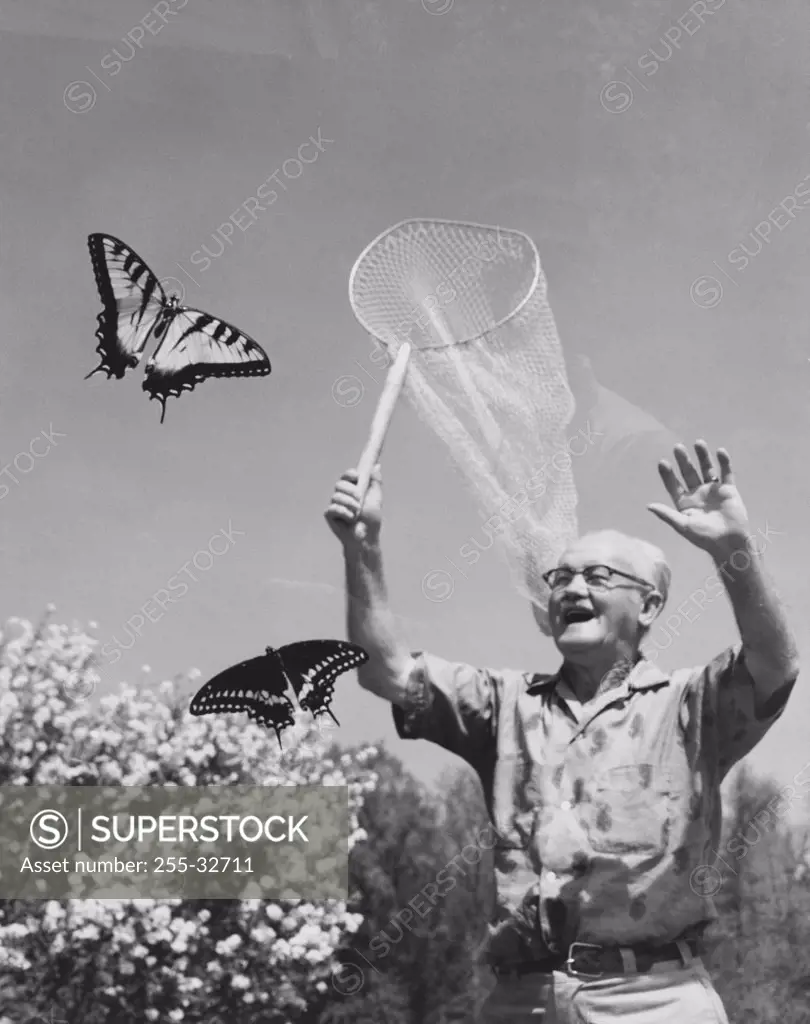 Senior man trying to catch butterflies