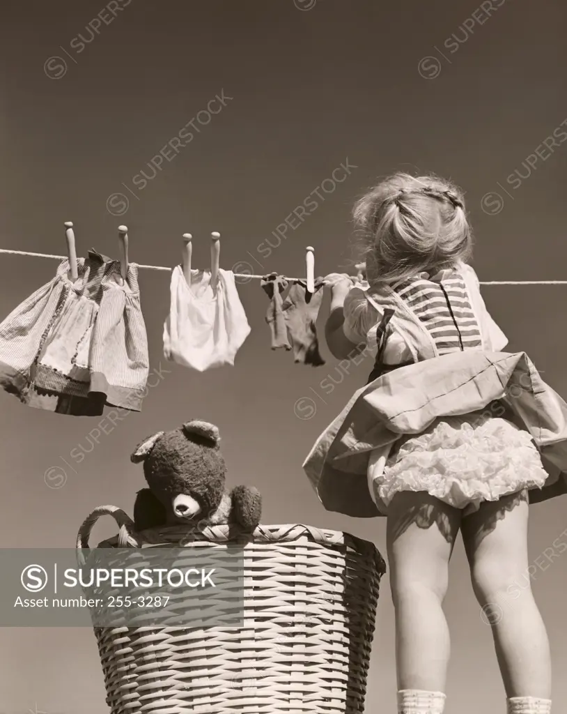 Rear view of a girl hanging clothes on a clothes line