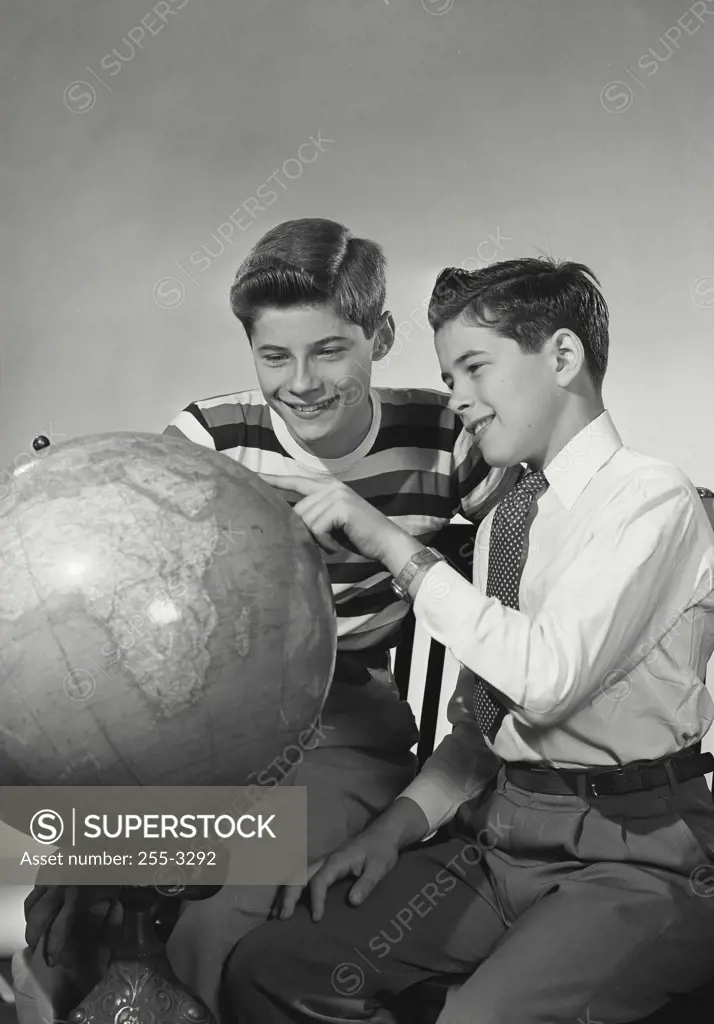 Vintage Photograph. Close-up of two teenage boys looking at a globe