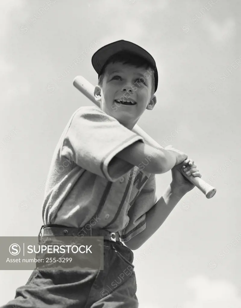 Young boy with baseball bat looking up at sky after hit