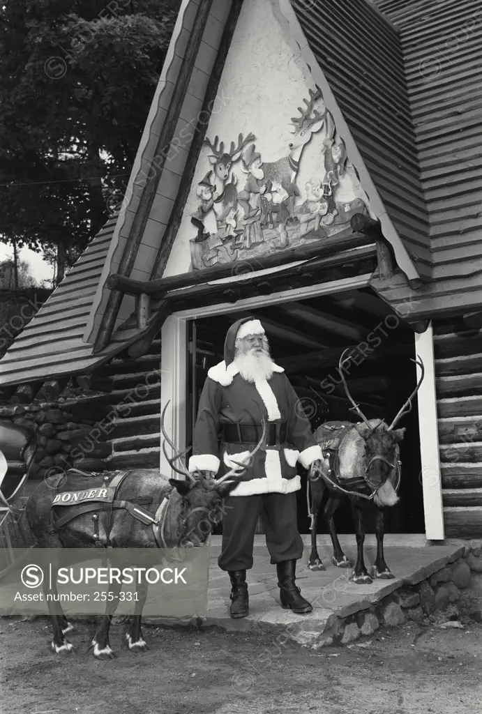 Vintage Photograph. Santa Claus standing with two reindeer in front of a building