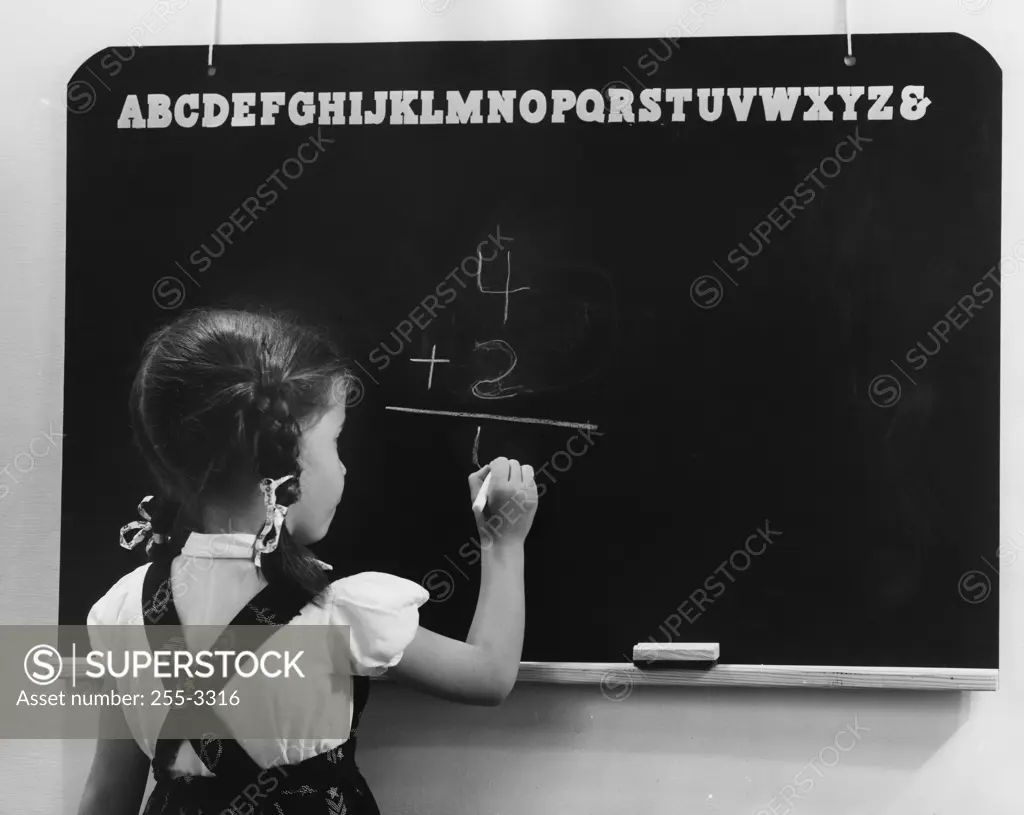 Rear view of a girl writing on a blackboard