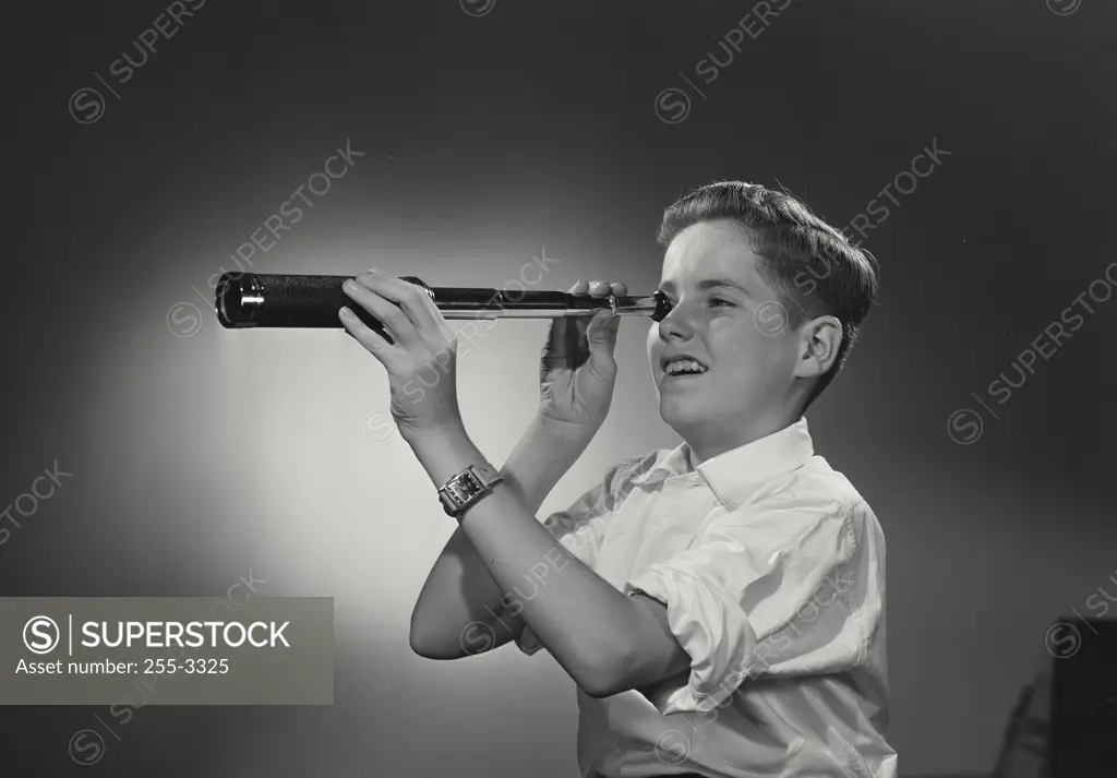 Vintage Photograph. Boy wearing white dress shirt looking through hand held telescope