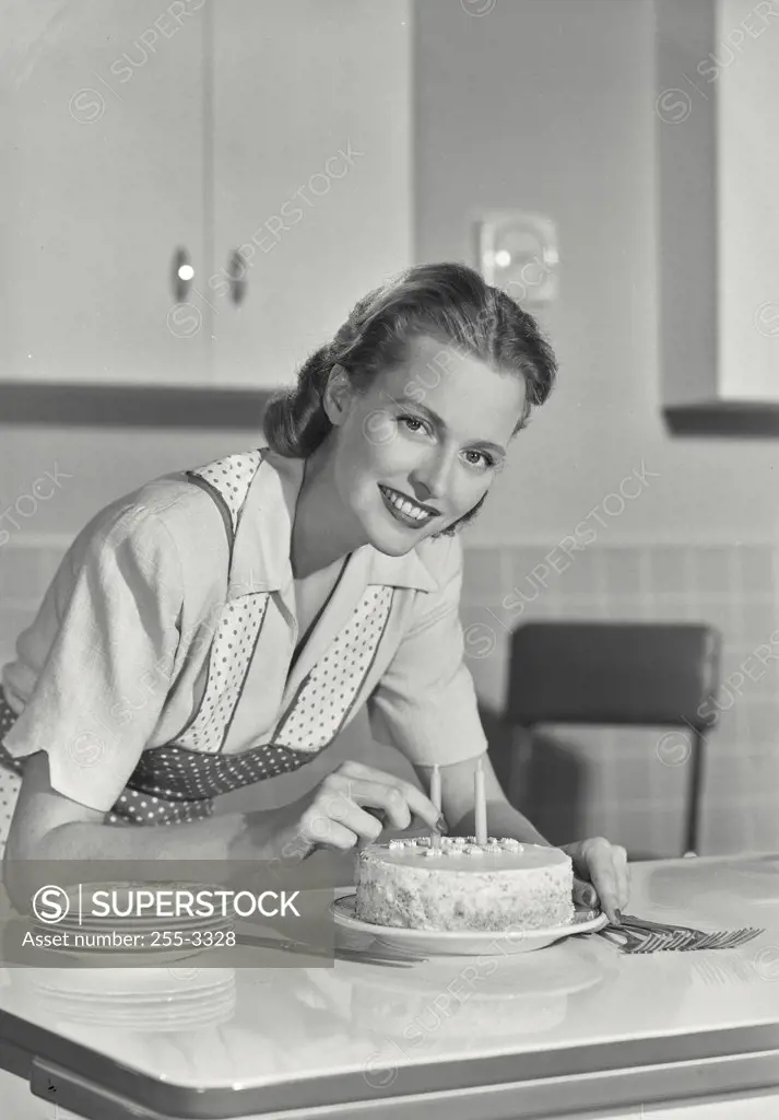 Vintage photograph. Portrait of a young woman decorating a birthday cake