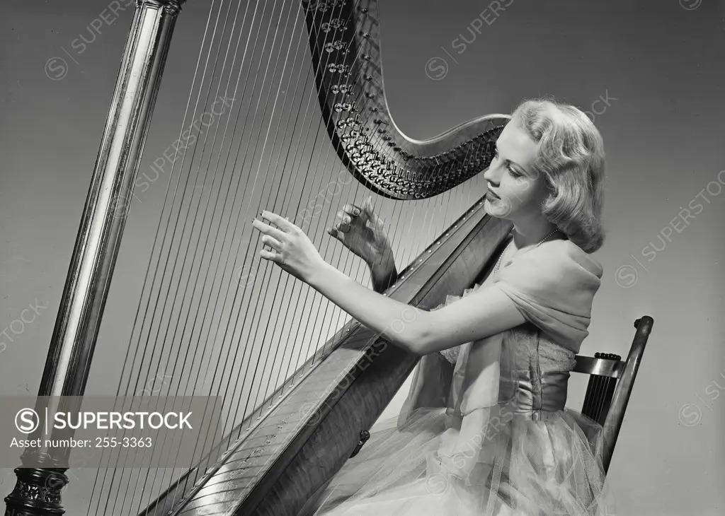 Vintage Photograph. Woman in dress smiling and playing Grand Pedal Harp. Frame 2
