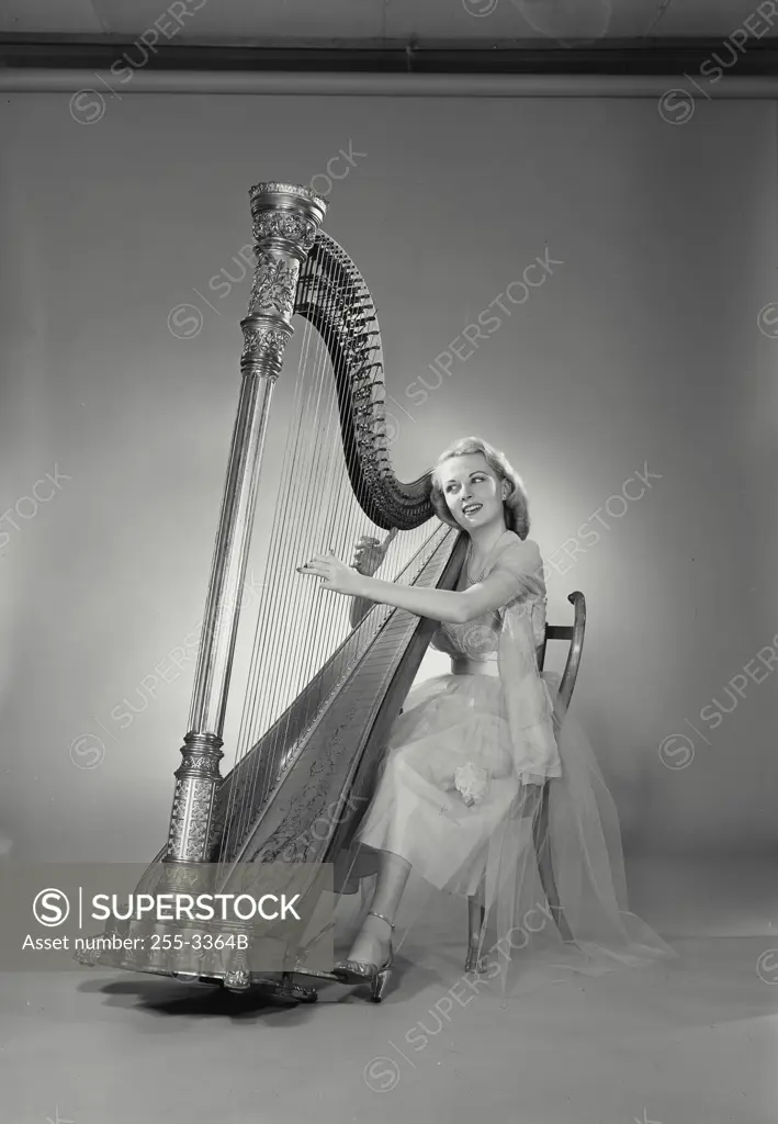 Vintage Photograph. Woman in dress sitting in chair playing Grand Pedal Harp. Frame 11