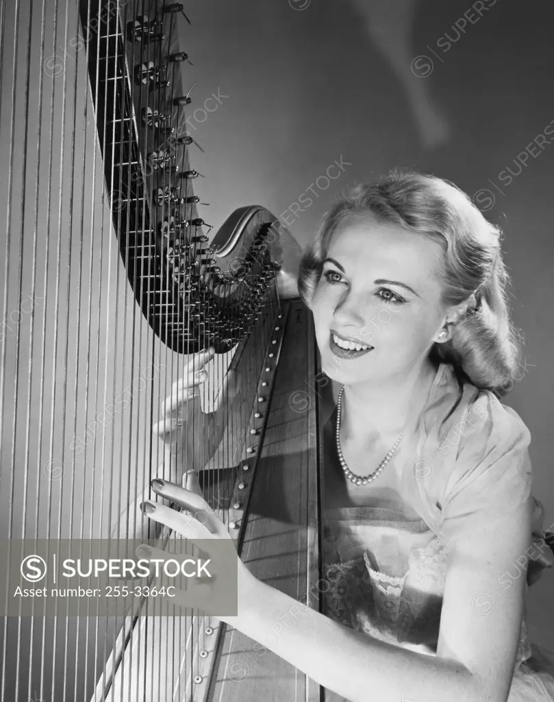 Young woman playing a harp and smiling