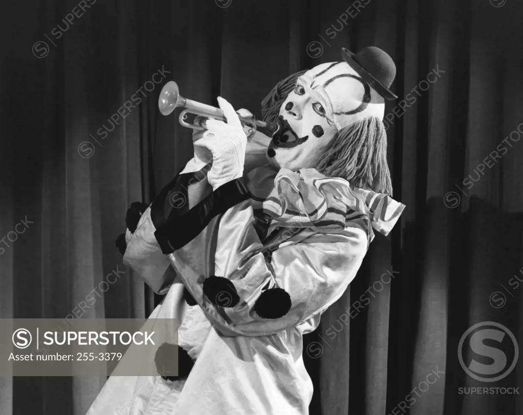 Side profile of a clown blowing a trumpet
