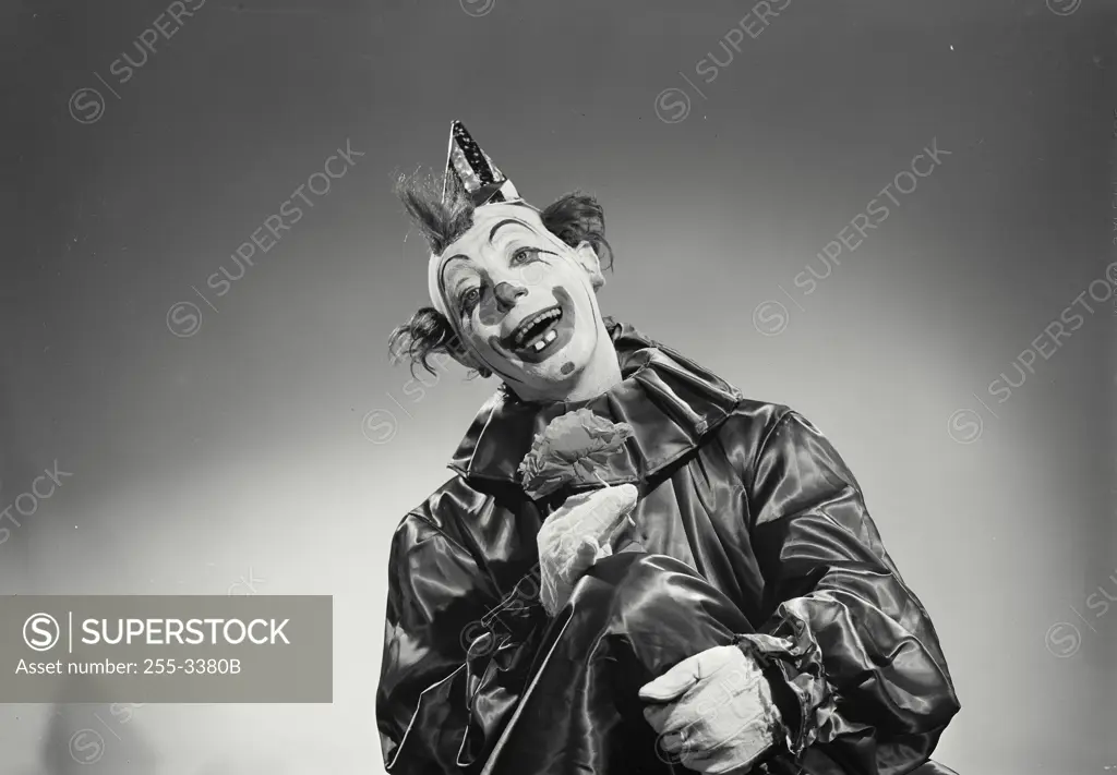 Vintage Photograph. Man dressed as clown in front of solid studio background
