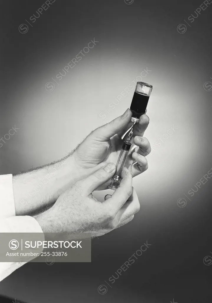 Vintage photograph. Close-up of a person's hand filling a syringe from a vial